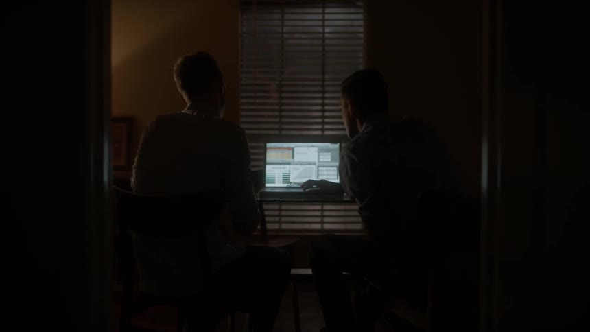 Two men sit in an office with a laptop