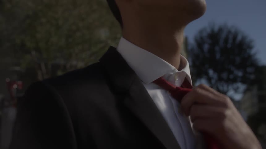 A man in a suit adjusts his tie while walking