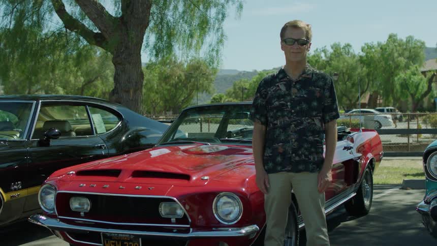 A man stands in front of a red sports car