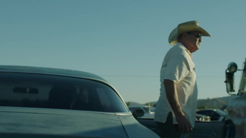 A man exits a car and waves