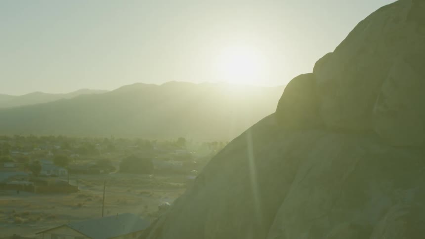 Sun shines over a hill and over buildings