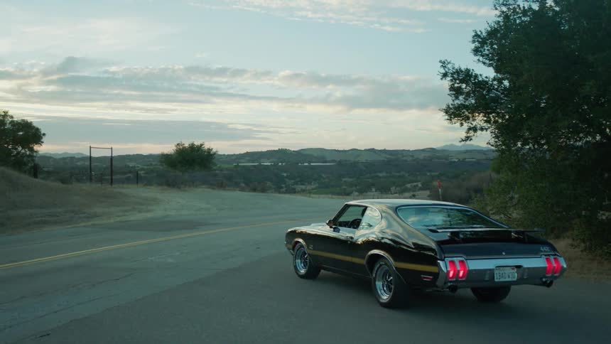 A late model american car is sitting pulled off on the side of a rural road