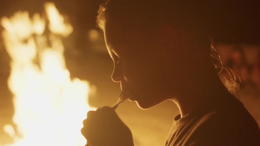 A young boy eats a smore by a campfire
