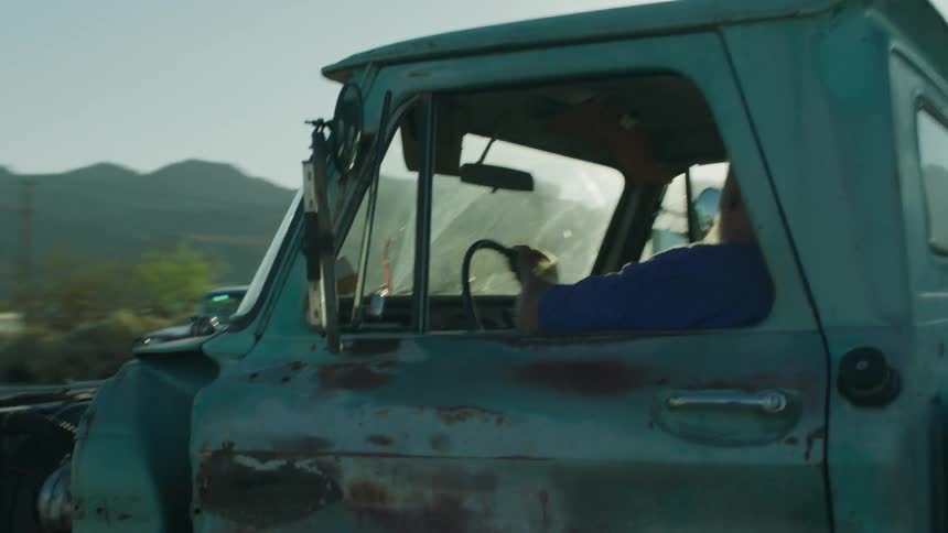A bearded man drives a beat up truck