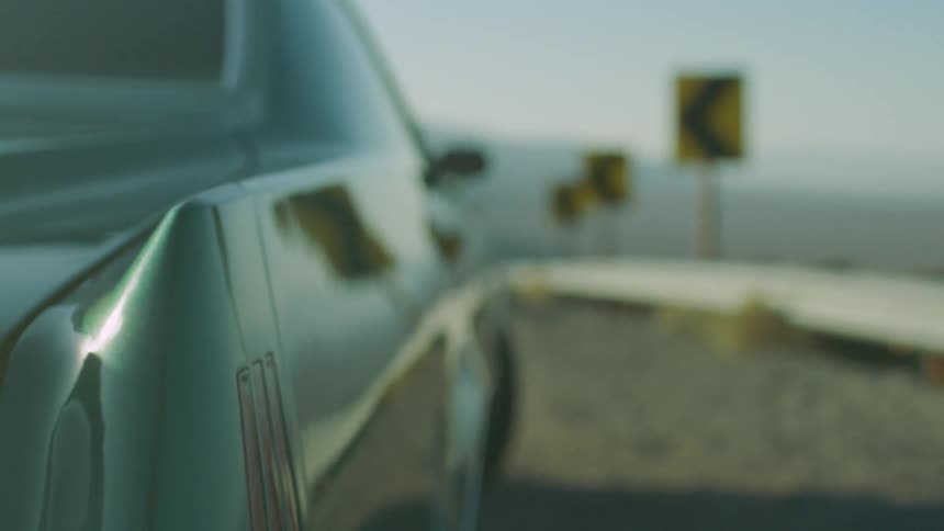 A car is packed on the side of the road that overlooks a desert valley