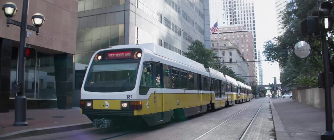 A train is driving through the downtown of a busy city
