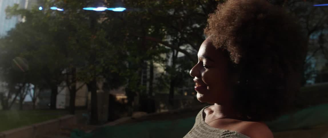 A black woman smiles outside under the sun
