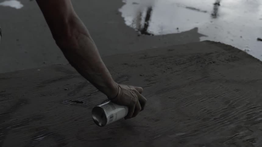 A man spray paints on the ground