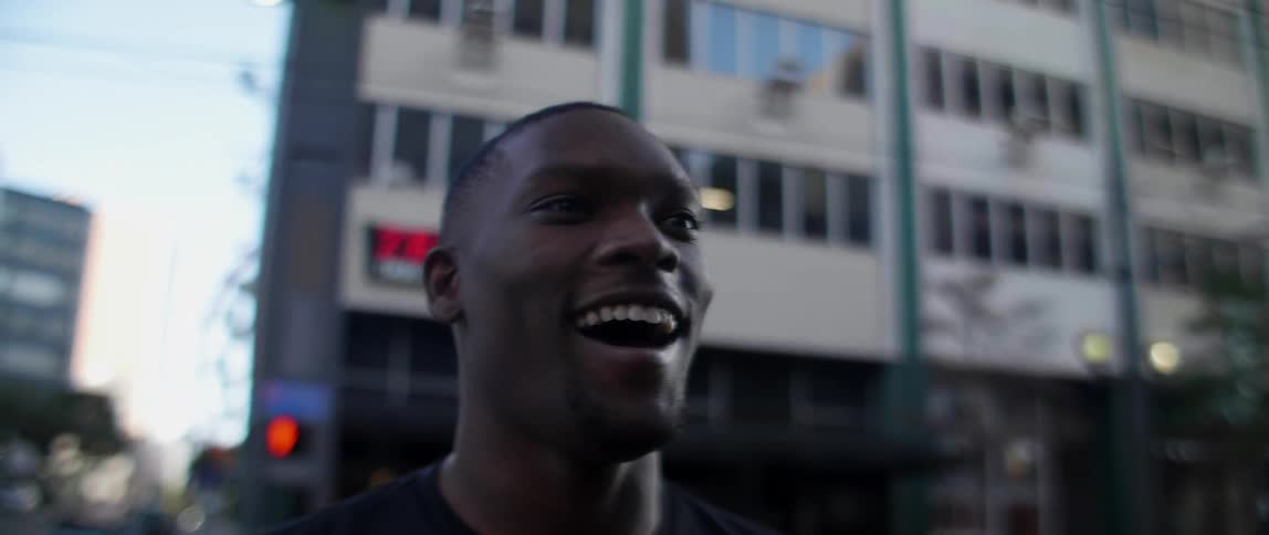 A black man smiles outside a building