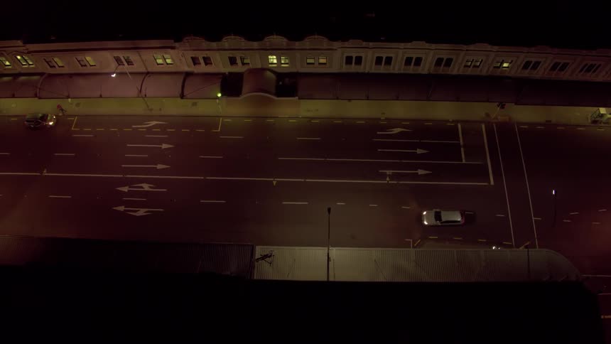 A vehicle drives down a city road at night