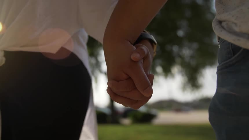 Two people hold hands outside