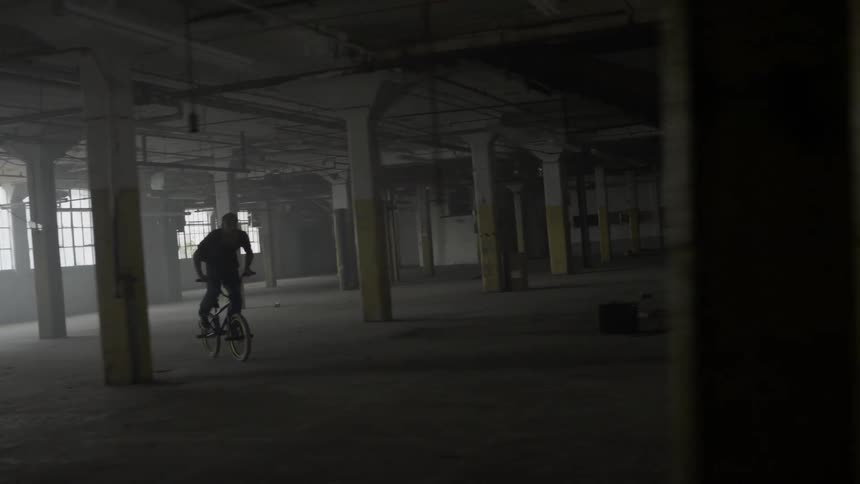 A man riding a bike through an empty warehouse