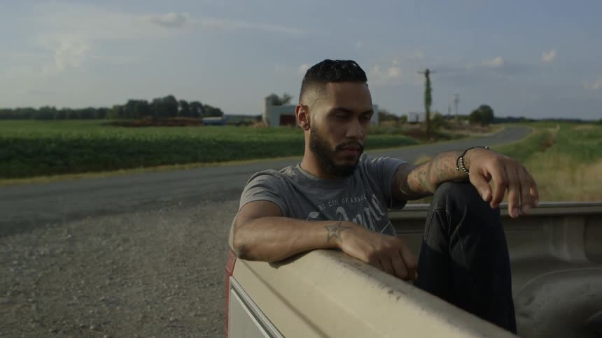 A man smokes a cigarette in the bed of a truck