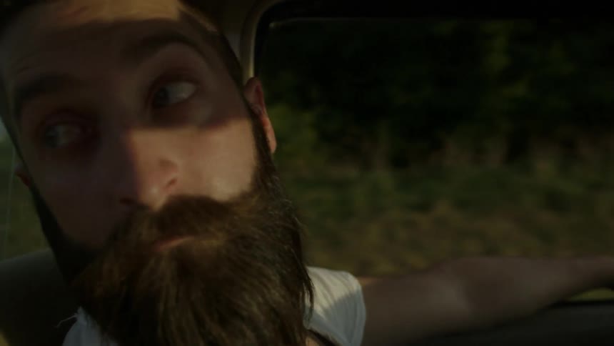 A man with a beard is driving down the road