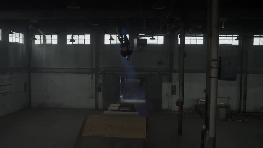 Man does a flip on a bicycle in a warehouse