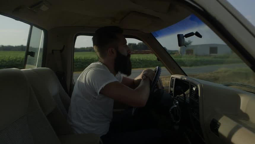 A man is sitting in his pickup with two people in the back