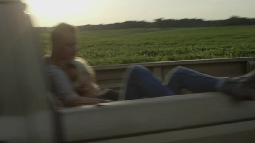 A couple of guys are riding in the back of a pick up truck