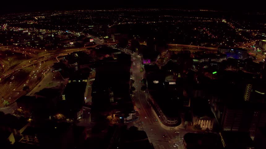 Cars drive on city streets at night