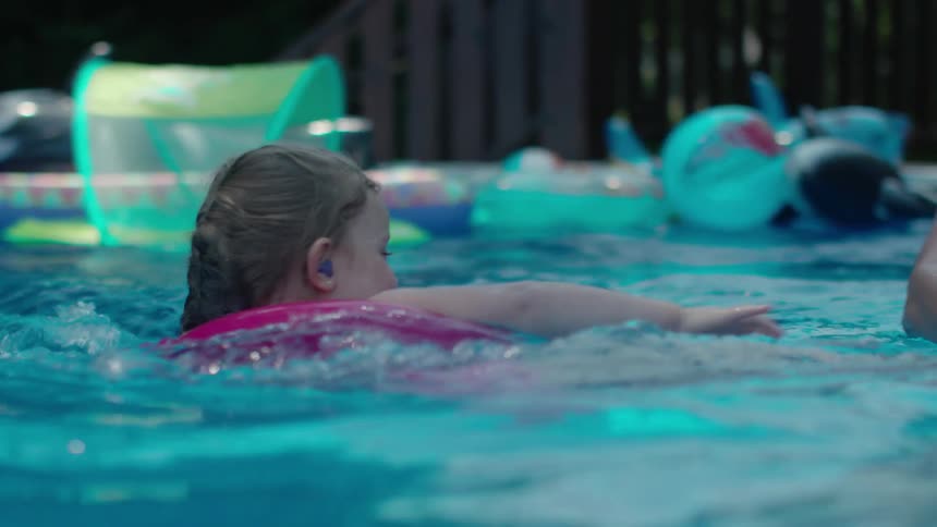 A mother plays with her children in a pool during the day
