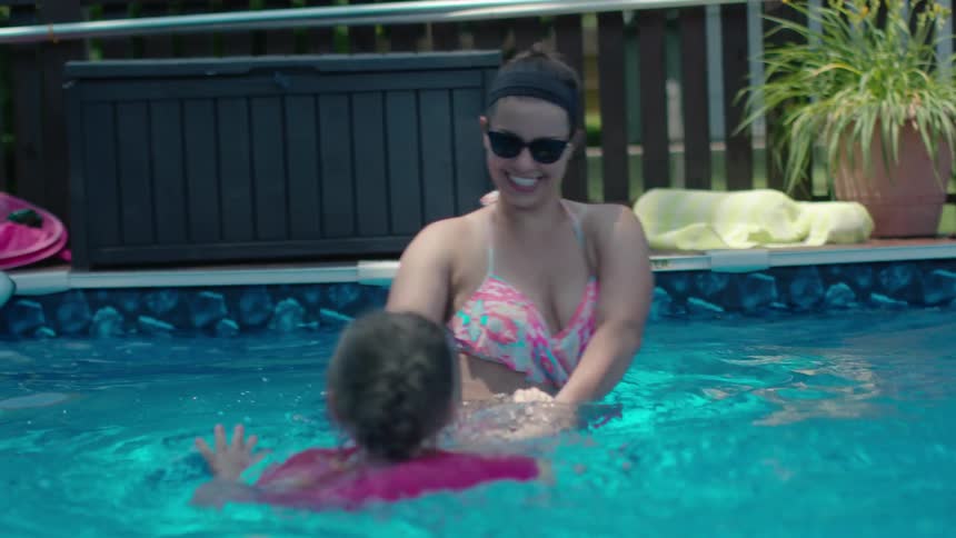 A woman smiling as she plays in the pool with her child