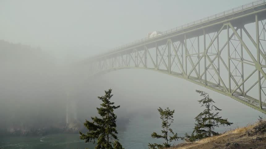 The truck travels over the bridge covered with fog
