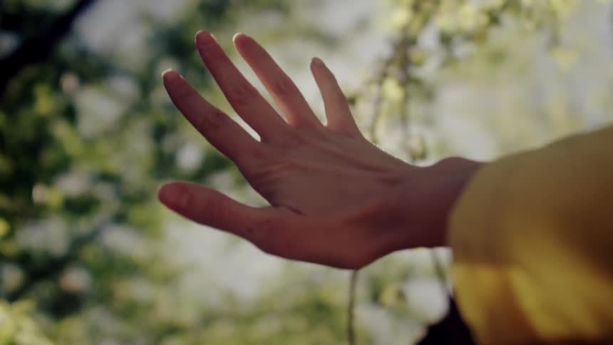 A woman is holding her hand up to the sun