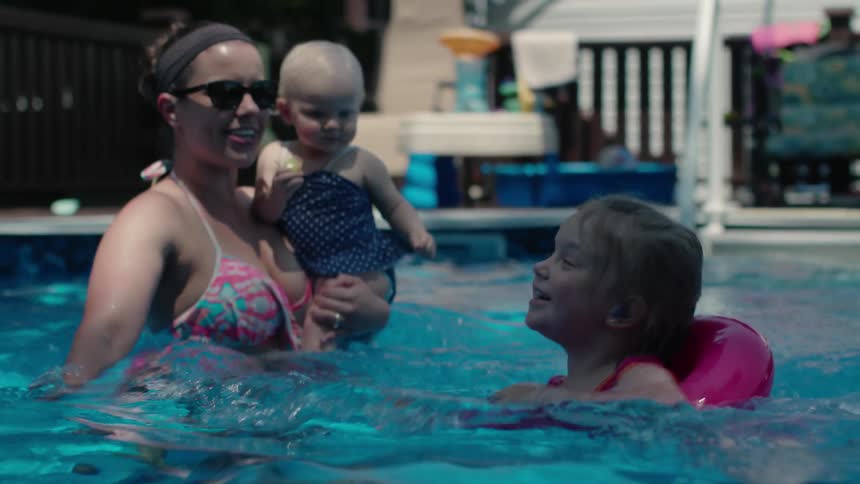 A mother and two kids are swimming in a pool