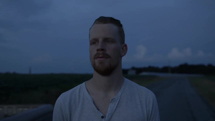 A man is standing on a field at dawn