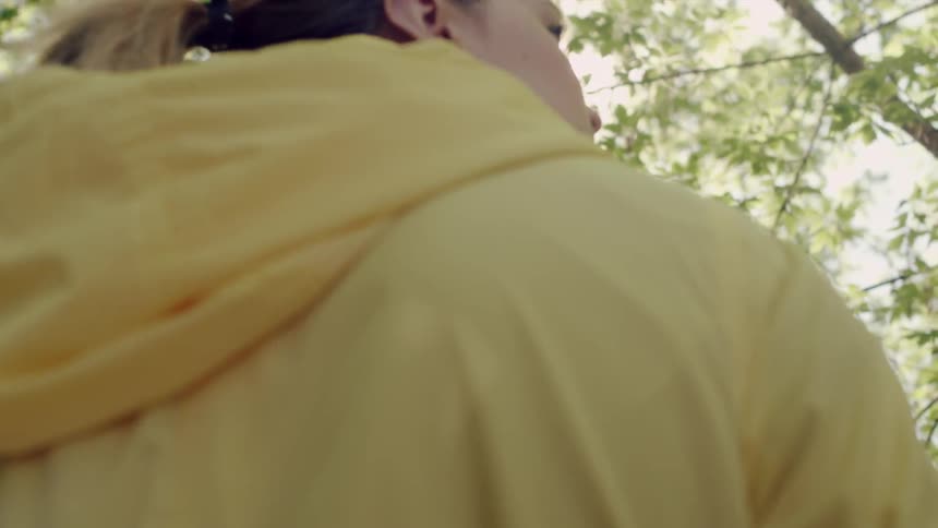 A woman wearing a yellow jacket is hiking outside