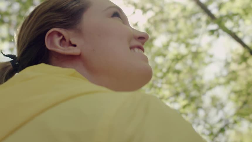 Woman smiling outside below trees and sunlight