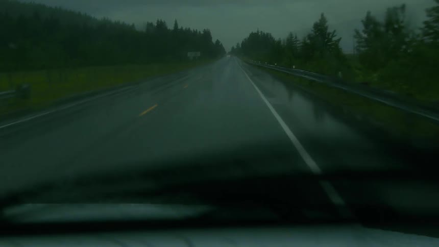 Car drives on a road while it rains