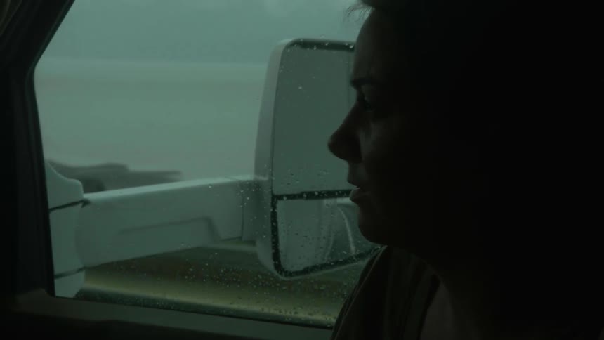 Woman sits in a vehicle talking on a cloudy day