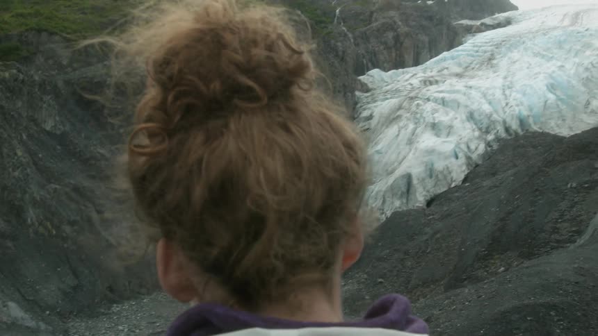 Woman stands in snowy mountains on a windy day