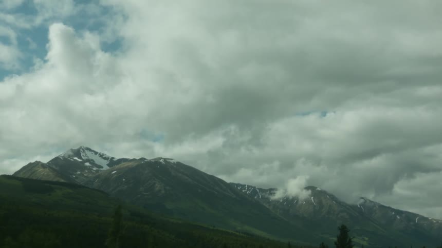 Clouds hang above mountains and trees