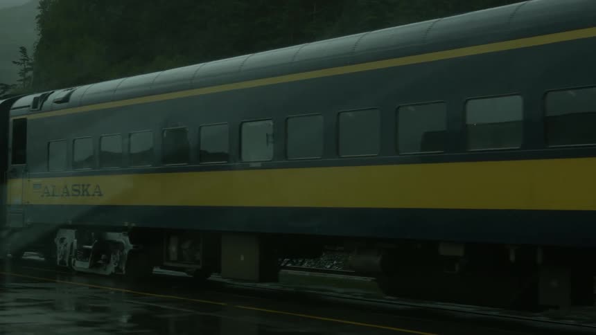 A train is being filmed from a passing car sitting in the rain