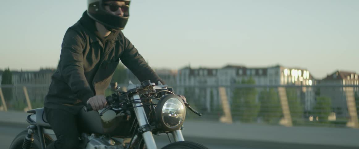 A man is riding a motorcycle across a bridge during the day