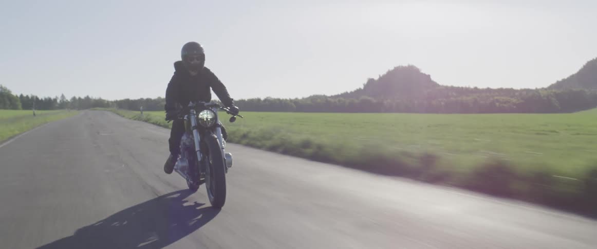 Person rides a motorcycle on a country road