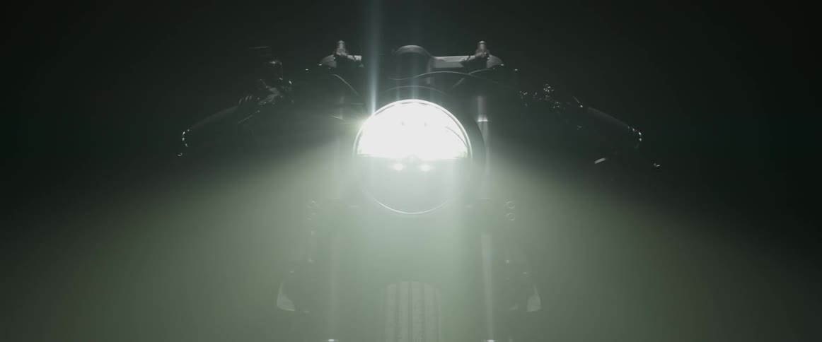 A motorcycle headlight shines on then off in the dark