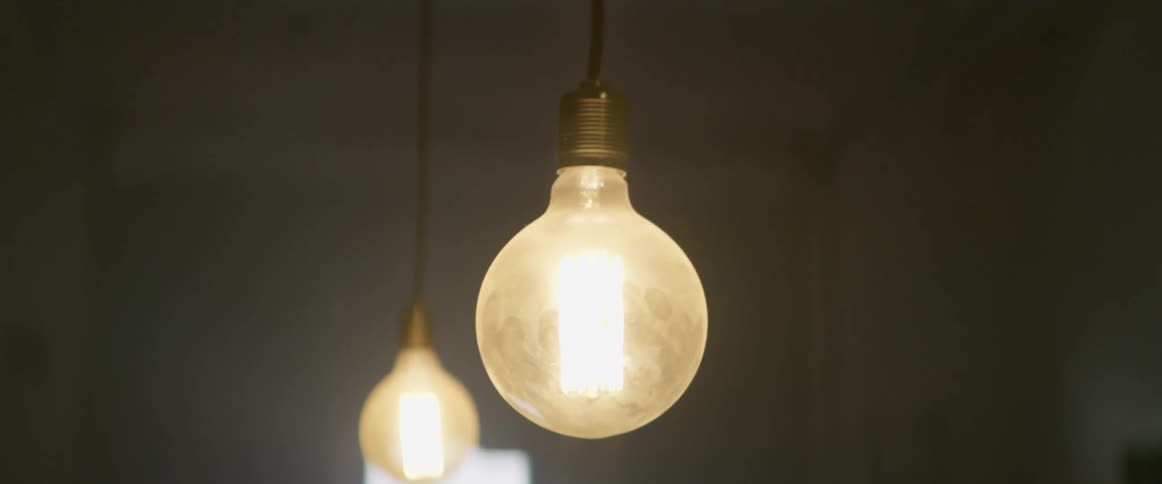 Glowing light bulbs hang from a ceiling