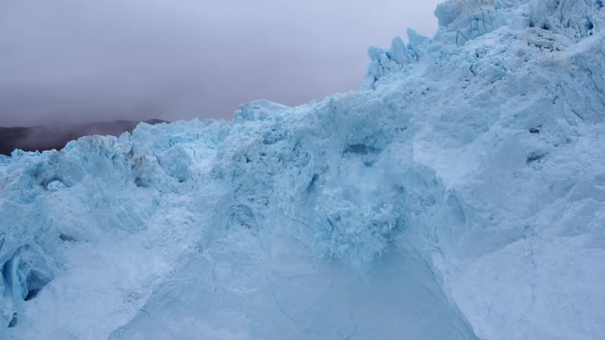 Snow collapses from the side of a glacier