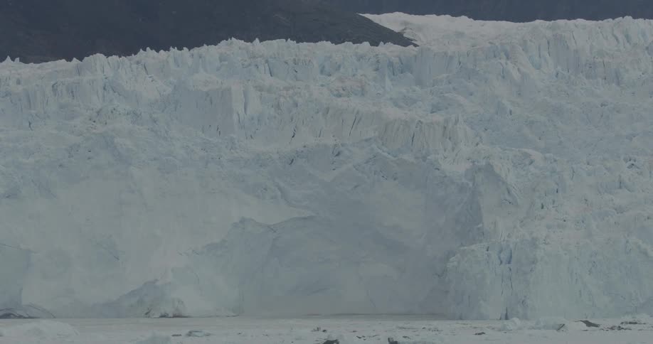 The large ice wall is white in color by the rocks