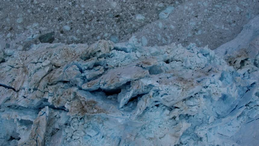 Ice and debris float in the ocean at the base of a glacier