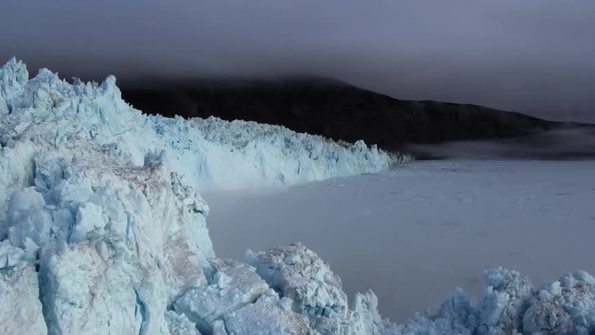 Fog hangs over the ocean below a glacier