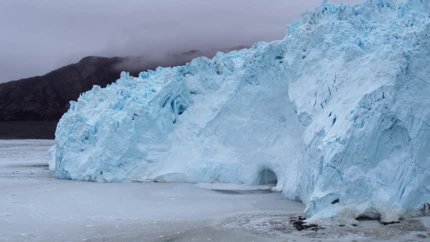 Snow and ice calves off a glacier causing ripples in the ocean