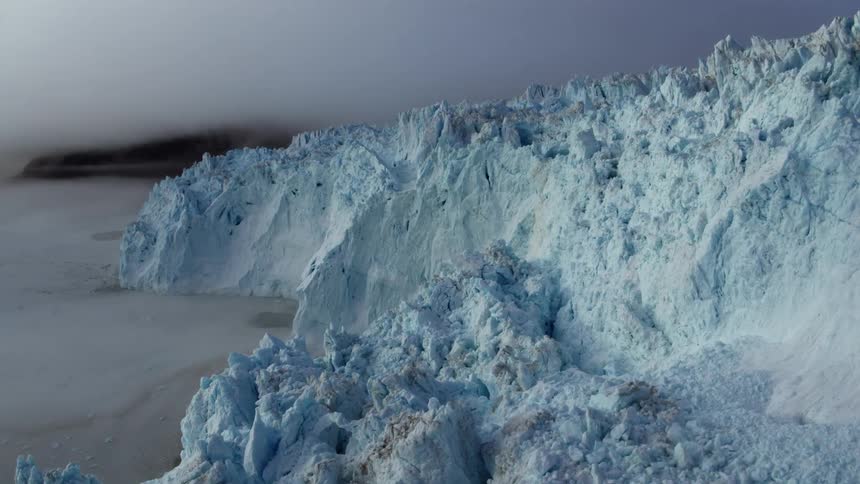 Fog hangs over the ocean below a glacier