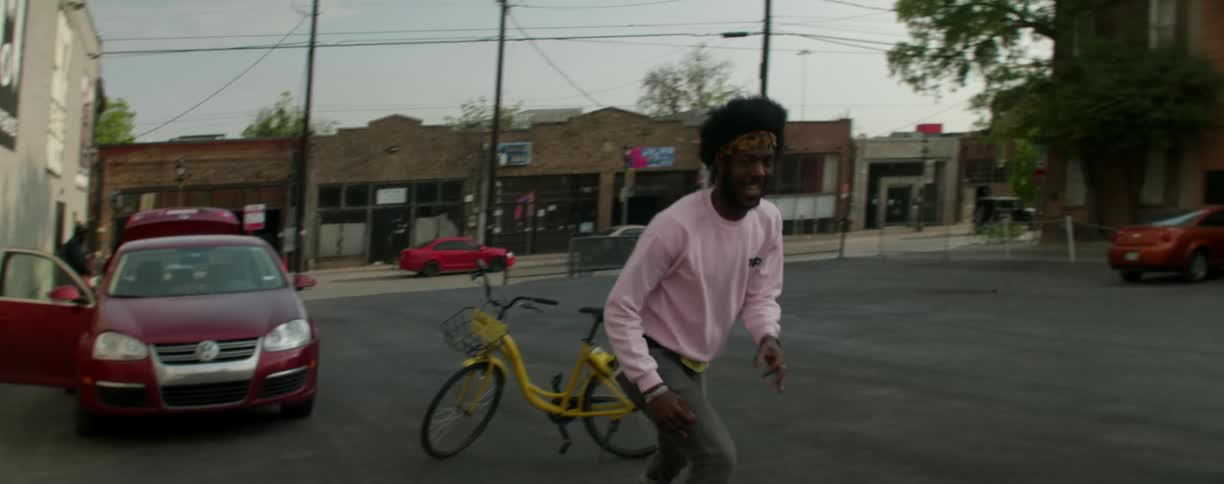 A skateboarder jumps over a bicycle as he is riding in a parking lot