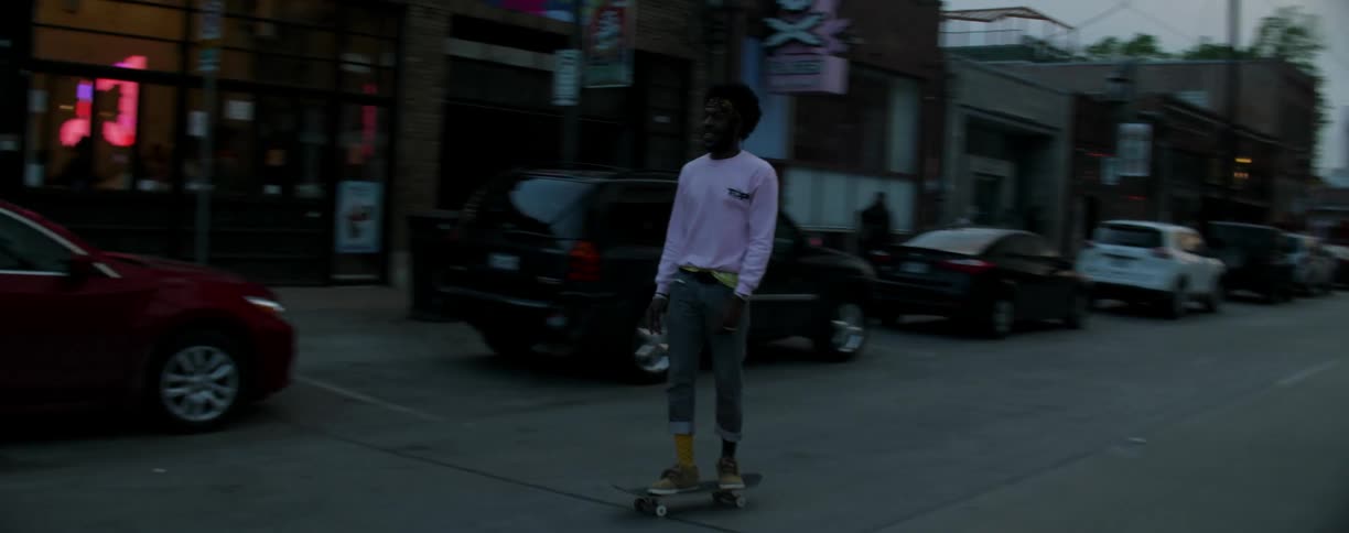 A man is riding his skateboard down the street at sunset