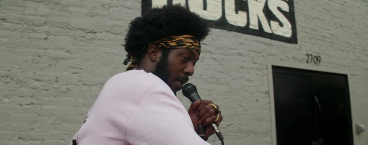 Man speaks into a microphone next to a building
