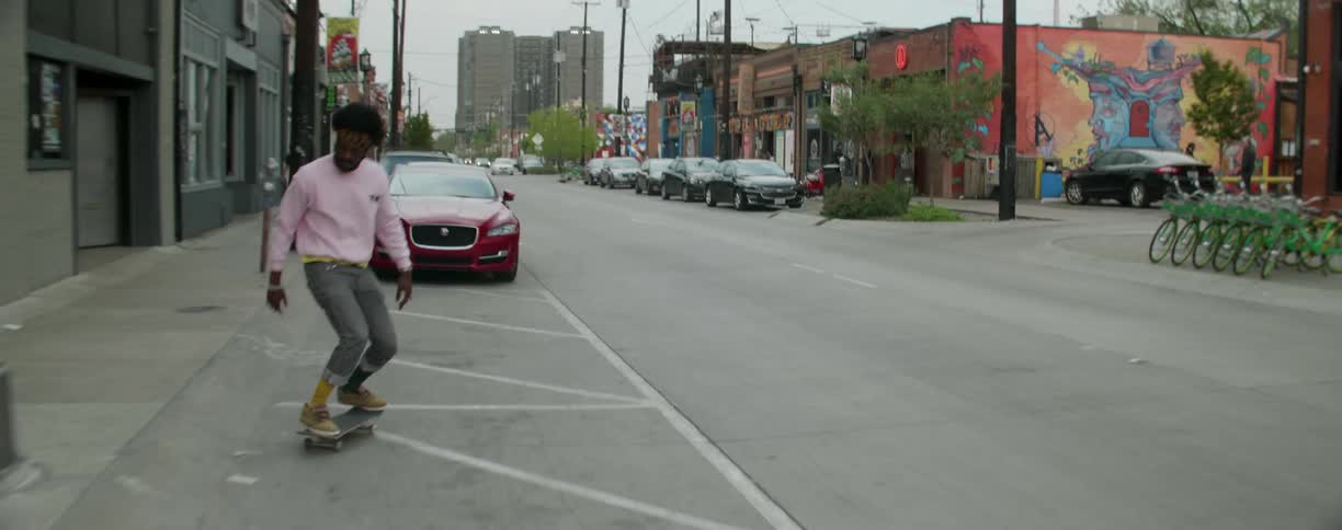 A black man skateboards down the street