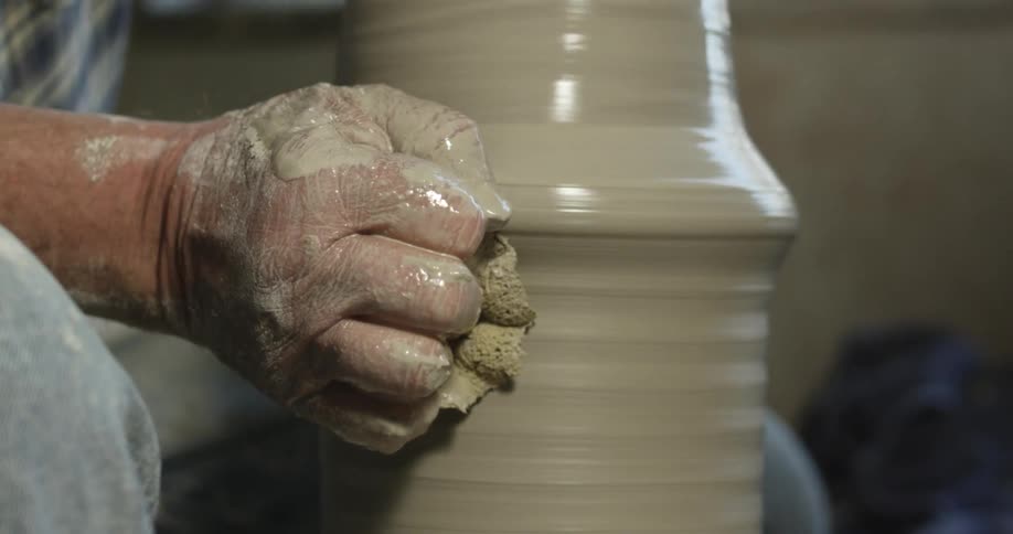 Person using pottery wheel and clay to create something